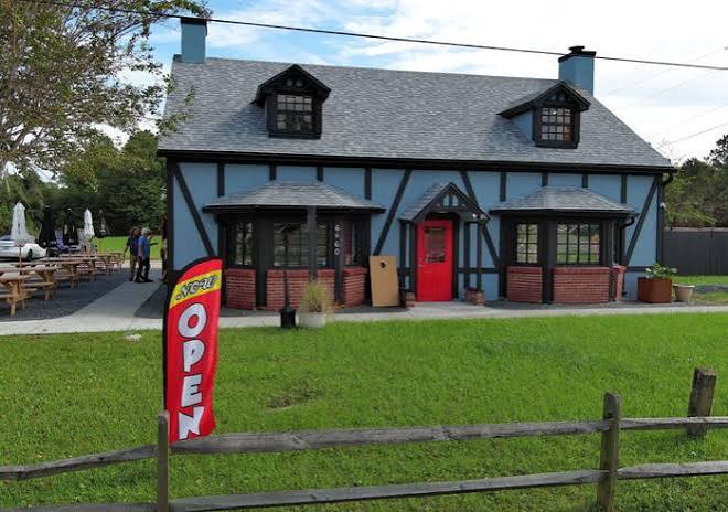The blue half-timbered cottage on US 1 with the red door and the OPEN flag out front